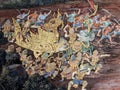 Within a Thai temple, a traditional mural painting captures a fierce battle scene,