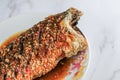 Thai Tradition food Deep fried fish topped with sweet and sour sauce on white plate serve to customer.Selective focus on Mable tab