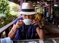 Thai woman with fedora hat sitting at cafe drinking coffee Royalty Free Stock Photo
