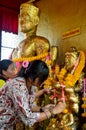 Thai Woman glid cover angel statue with gold leaf at Phra Kal Sh Royalty Free Stock Photo