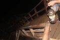 Thai Woman is holding a kerosene lamp in her hands while walking down the massive wodden stairs in the Cave