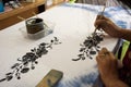 Thai woman people artist painting pattern with natural color indigo on fabric shawl scarf on table in workshop studio at house in