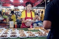 a Thai woman, a saleswoman cook at the market sells meat kebabs to a customer - traditional Thai food. street photo Royalty Free Stock Photo