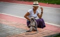 Thai woman in sarong and white fedora looking at Duskey monkey