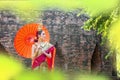 Thai Woman In Traditional Costume with umbrella of Thailand. Female Traditional Costume with thai style temple background. Wat