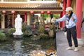 Thai woman visit and feeding food to fancy carp in pond of chinese garden at Thai-Chinese Cultural Center in Udon Thani, Thailand Royalty Free Stock Photo