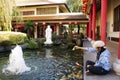 Thai woman visit and feeding food to fancy carp in pond of chinese garden at Thai-Chinese Cultural Center in Udon Thani, Thailand Royalty Free Stock Photo