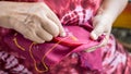 Thai woman wearing a red blouse using a needle and yellow thread