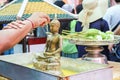 Thai women praying, buddhist ceremony. Buddha statue, citrus juice squeezed on it, offering Royalty Free Stock Photo