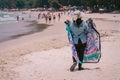 Thai women selling colorful textiles on tourist beach walks along seashore line. Rear photo, Thailand