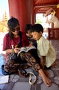 Thai women teach burmese children reading book at Shwezigon Pagoda