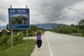 Thai women traveler posing for take photo with distance sign guide pole