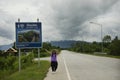 Thai women traveler posing for take photo with distance sign guide pole