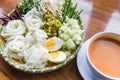 Thailand food vermicelli noodle boiled eggs and fresh vegetables on plate with curry soup bowl served wooden table - Thai rice