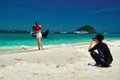 THAILAND, PHUKET, 19 MARCH 2018 - Young man take photos on smartphone girl on tropical beach, amid sea bay. Young chinese couple. Royalty Free Stock Photo