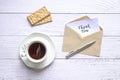 Thank you card inside brown envelope next to cup of tea, biscuits and pen Royalty Free Stock Photo