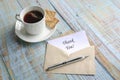 Thank you card inside brown envelope with pen  next to cup of tea and biscuits Royalty Free Stock Photo