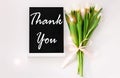 Thank You card message sign on black chalkboard with tulip flowers on white background flat lay.Blackboard greeting text Royalty Free Stock Photo