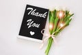 Thank You card message sign on black chalkboard with tulip flowers on white background flat lay.Blackboard greeting text Royalty Free Stock Photo