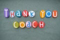 Thank you Coach, creative message composed with multi colored stone letters over green sand