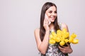 Thank you for flowers. Portrait of a happy young girl in dress talking on mobile phone while holding big bouquet of yellow tulips Royalty Free Stock Photo