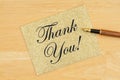 Thank you greeting card on gold glitter greeting card with pen on textured wood