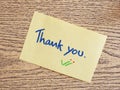 Thank you handwriting on post-it notes on a wooden board.