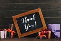thank you lettering on chalkboard in frame with various gift boxes against