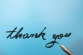 thank you message written with black ink on stained glass texture, with a pen nib, with blue background Royalty Free Stock Photo