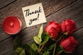 Thank you note and red roses with aroma candles on a wooden background: concept of a romantic gift and thanks Royalty Free Stock Photo