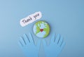 Thank you sign with paper hands in blue gloves on a medical background