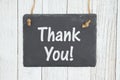 Thank you text on a hanging chalkboard on weathered whitewash textured wood