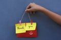 Thank you vintage style word on colorful origami paper notes. Young girl holding thank you sign rope with smiling emoticon.