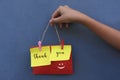 Thank you vintage style word on colorful origami paper notes. Young girl holding thank you sign rope with smiling emoticon on blue