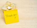 Thank you words on sticky note with gold gift box on wood background Royalty Free Stock Photo
