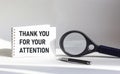 Thank you for your attention - a notebook is on a white background, next to a magnifying glass Royalty Free Stock Photo