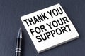 THANK YOU FOR YOUR SUPPORT text on the sticker with pen on the black background
