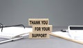 THANK YOU FOR YOUR SUPPORT text on wooden block with notebook,chart and calculator, grey background Royalty Free Stock Photo