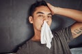 Thanks flu, its not like I had things to do. a young man blowing his nose while recovering from an illness in bed at Royalty Free Stock Photo