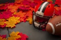 Thanksgiving american football game concept with copy space, a generic helmet and ball on the pavement surrounded by fall foliage