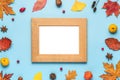 Thanksgiving autumn photo frame. Dried leaves, flowers, nuts, berries on blue background. Flat lay, mock up