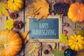 Thanksgiving background with chalkboard. Autumn pumpkin and fall leaves on wooden table.