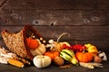 Thanksgiving cornucopia filled with autumn pumpkins and vegetables against dark wood