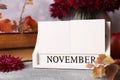 Thanksgiving day, holiday celebrated every fourth Thursday in November. Block calendar and autumn leaves on grey table, closeup