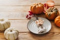 Thanksgiving day serving table with plate, taleware, pumpkins and leaves on wooden background Royalty Free Stock Photo