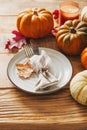 Thanksgiving day serving table with plate, taleware, pumpkins and leaves on wooden background Royalty Free Stock Photo