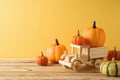 Thanksgiving decor concept with toy truck and pumpkin decor on wooden table over yellow background. Autumn season greeting card Royalty Free Stock Photo