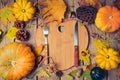 Thanksgiving dinner background with heart shape board. Autumn pumpkin and fall leaves on wooden table.