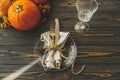 Thanksgiving dinner table setting. Stylish plate with cutlery, linen napkin and pumpkin with autumnal flowers on rustic table. Royalty Free Stock Photo