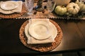 Thanksgiving formal table setting with pumpkin embossed dishes and natural fiber runner and napkins and woven place mats